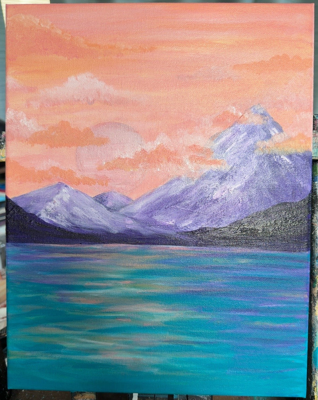Peach sunset over mountains and blue water